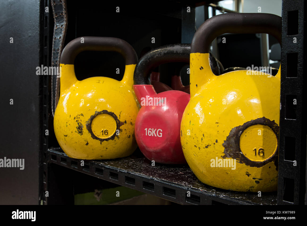 Jeu de colorful usé kettlebells sur une étagère métallique dans une salle de sport. Banque D'Images
