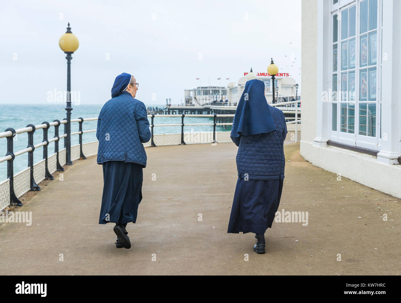 Paire de moniales marche sur une jetée au bord de la mer en Angleterre, Royaume-Uni. Banque D'Images