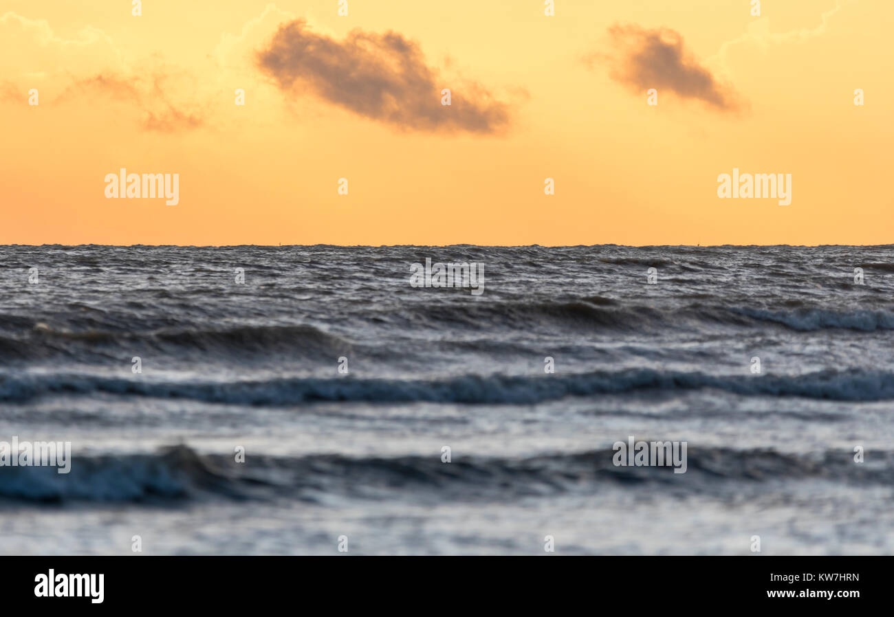 Mer à partir d'un angle faible avec orange ciel du soir en hiver. Banque D'Images