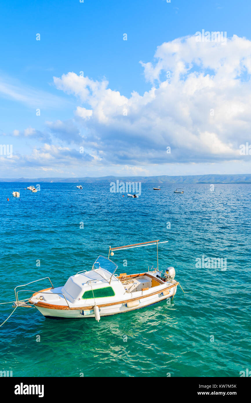 Bateau de pêche blanche sur la mer bleue et ciel ensoleillé avec des nuages blancs dans bol port, l''île de Brac, Croatie Banque D'Images