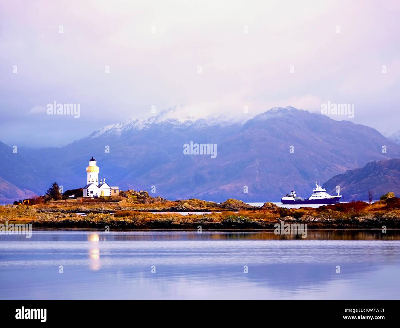 Célèbre Isle Ornsay avec tour Phare, île de Skye, Écosse, Royaume-Uni. Les montagnes enneigées en arrière-plan. Banque D'Images