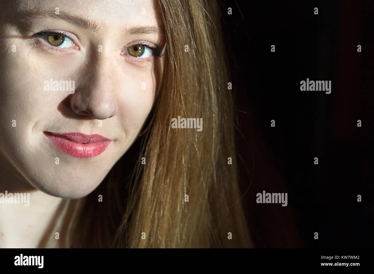 Portrait of a young blonde woman looking at camera, portrait gros plan, fond noir et la lumière. Banque D'Images