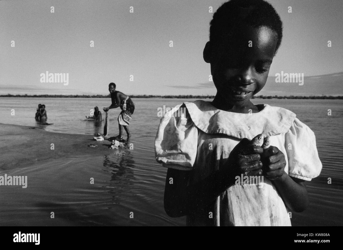 Inondations au Mozambique Mars 2000 ; une jeune fille tient deux petits poissons capturés par sa mère à l'aide d'un morceau de tissu comme un filet. Mombane Banque D'Images