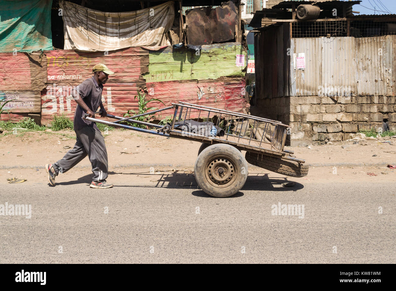 Un homme africain pousse sa charrette ou mkokoteni sur le bord de la route, Nairobi, Kenya, Afrique de l'Est Banque D'Images