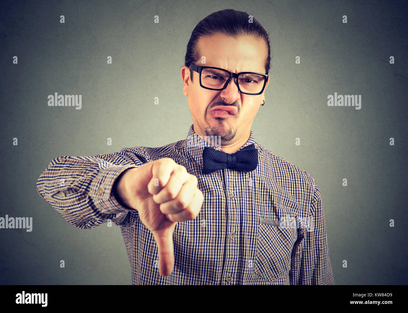 Jeune homme à lunettes officielles montrant non avec le pouce vers le bas à la caméra et à froncer les sourcils. Banque D'Images