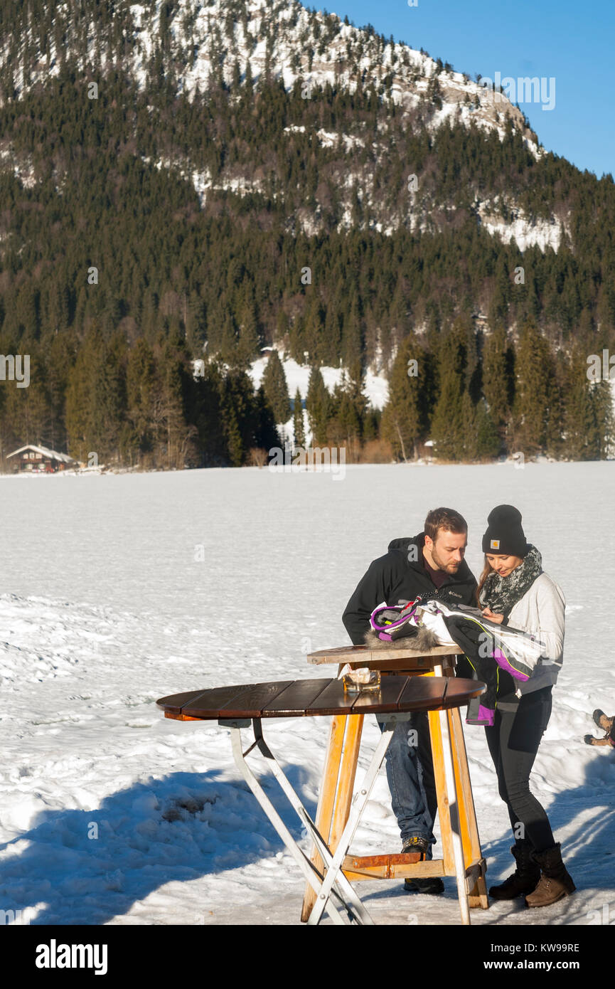 Un couple rassemble des forces canadiennes tout en regardant des photographies à une table par le lac MÃ¼nchen Spitzingsee. Banque D'Images