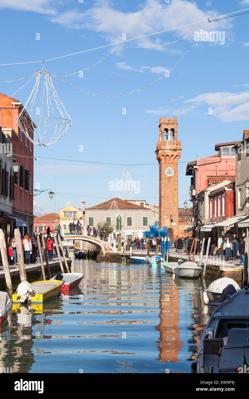Murano, Venise, Vénétie, Italie, voir le long du Canal Vetrai la Tour de l'horloge dans le Campo San Stephano reflète dans l'eau , groupe de touristes Banque D'Images