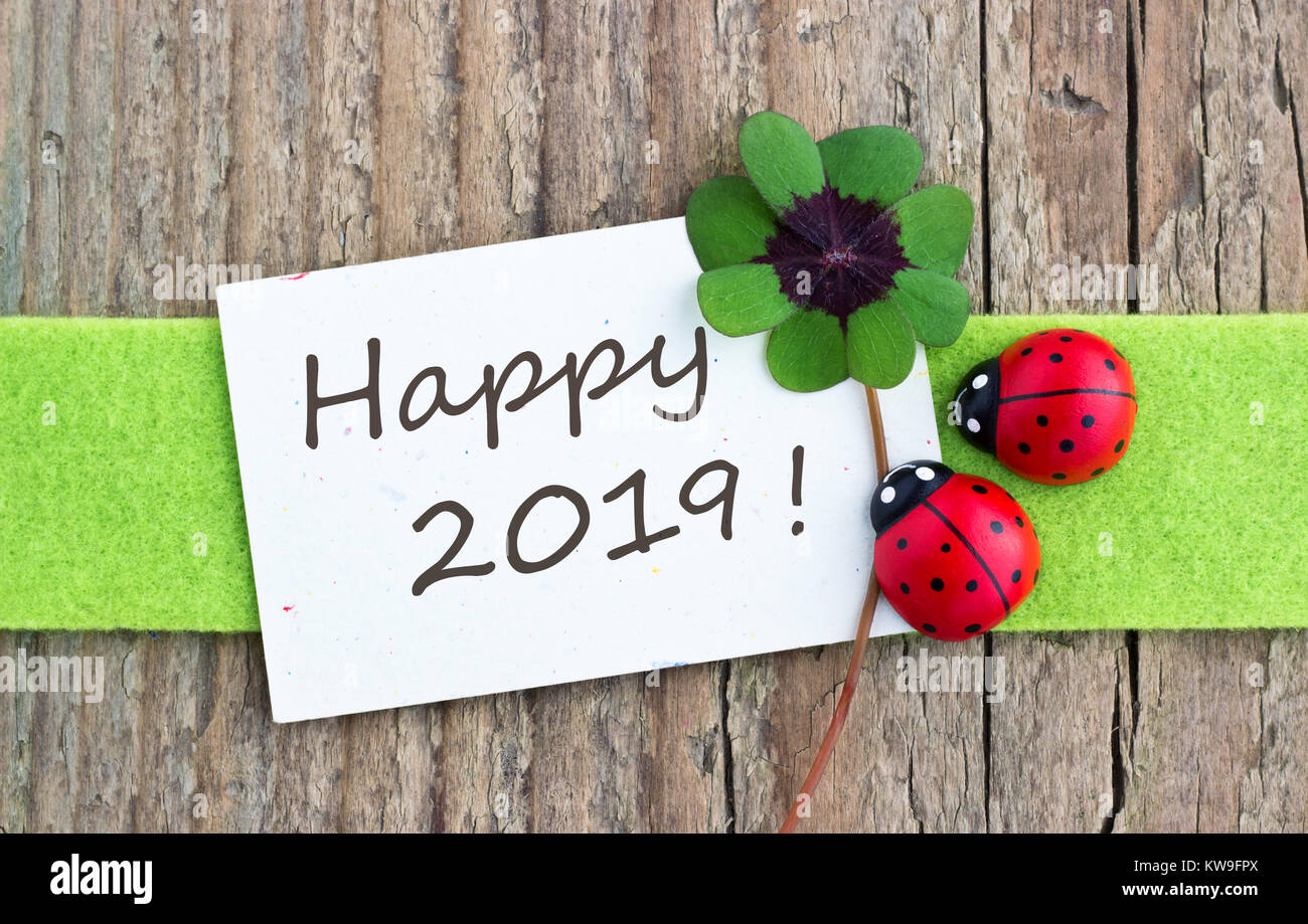 Carte de Nouvel An avec des feuilles le trèfle et coccinelles sur fond de bois Banque D'Images