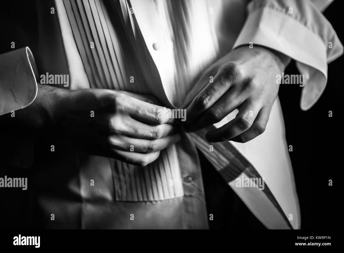 Photo en noir et blanc d'un homme à boutonner sa robe chemise. Banque D'Images