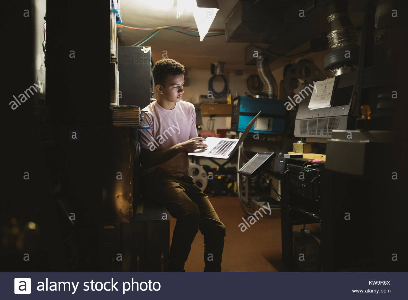 Tween mixed race boy using laptop in projectionniste de cinéma Banque D'Images