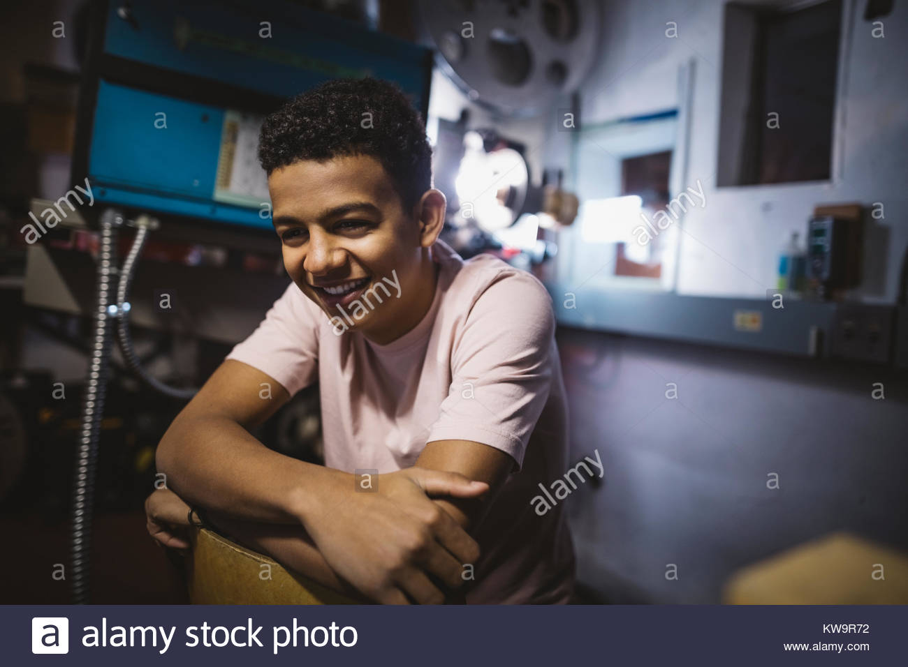 Sourire,rire mixed race boy tween dans projectionniste de cinéma Banque D'Images