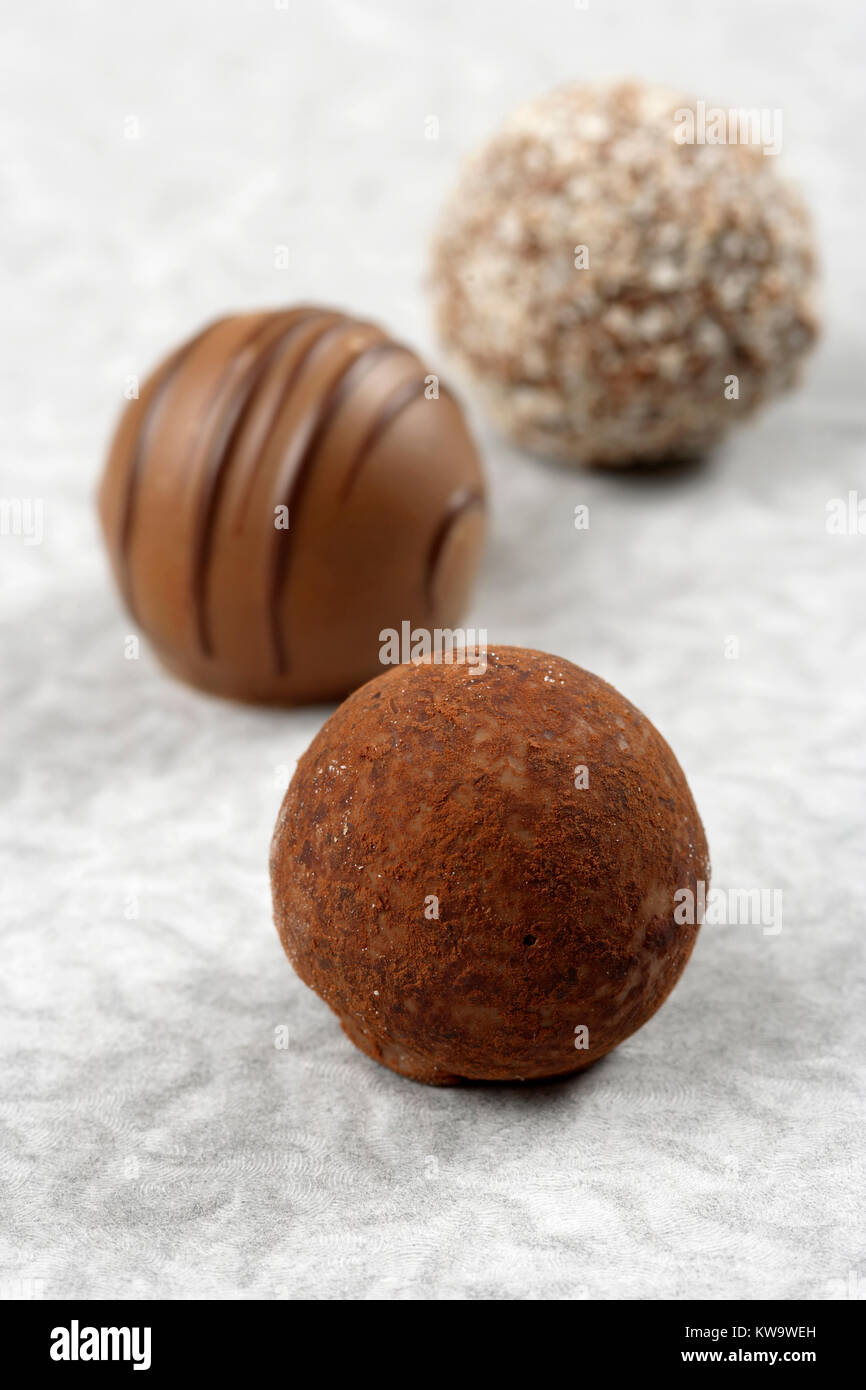 Photo de trois truffes au chocolat sur le papier texturisé. Très faible profondeur de champ, en se concentrant sur la première truffe. Banque D'Images