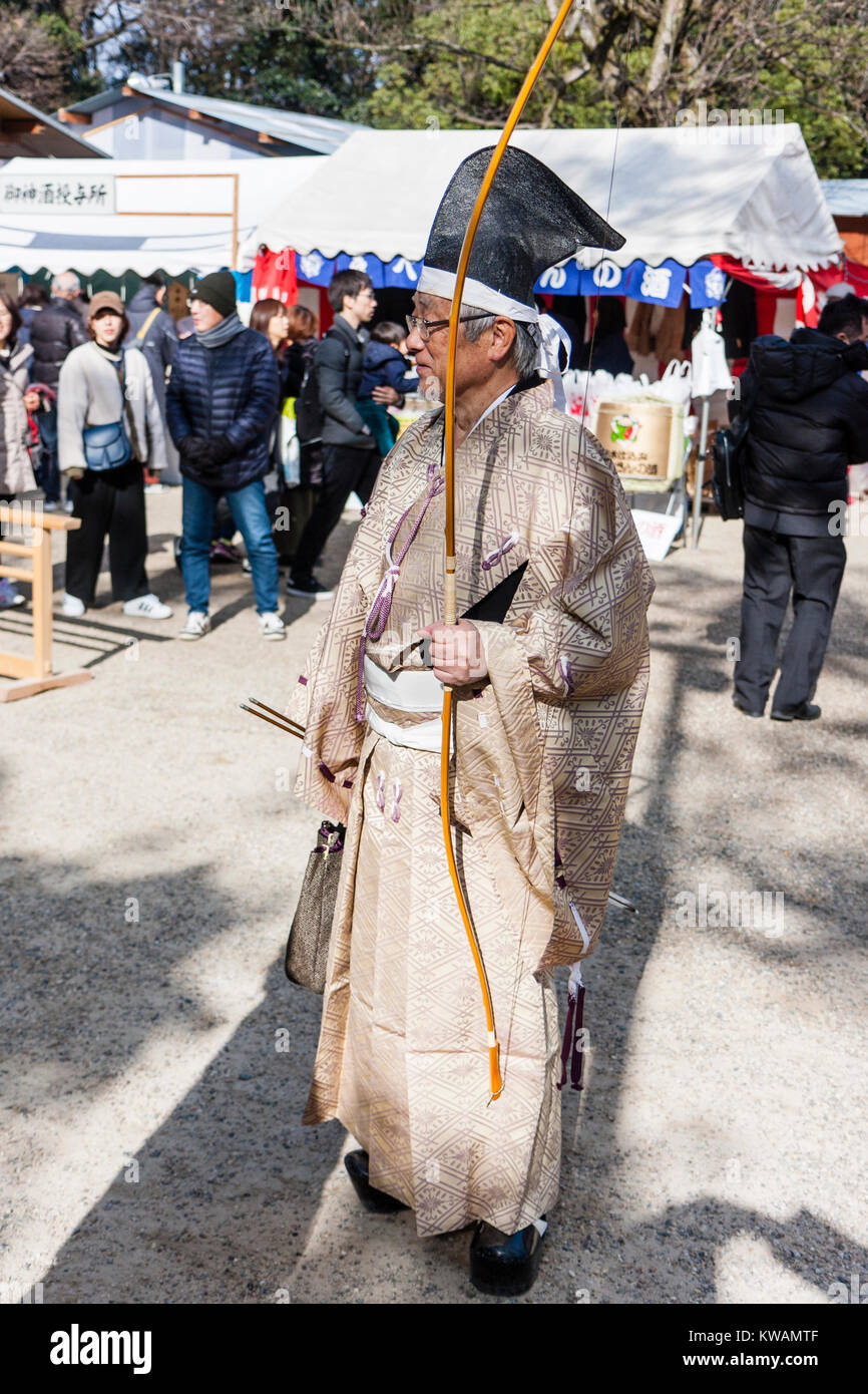 Le Japon, Nishinomiya Sanctuaire Shinto nouvelle année. Homme âgé archer habillé en style période Heian, marche à travers le culte terrain après un nouveau concours de tir à l'année courante, pour le Nouvel An et les autres jours de fête dans les sanctuaires japonais. Banque D'Images