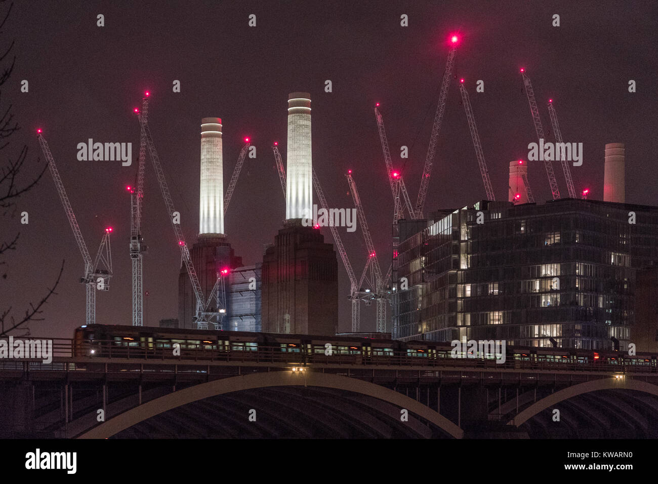 Londres, Royaume-Uni. 09Th Jan, 2018. Un train sur Chelsea Bridge et, en arrière-plan, voyants lumineux rouges sur des grues autour de la Battersea Power Station, qui est actuellement en cours de réaménagement, à Londres. Date de la photo : Le mardi, 2 janvier, 2018. Credit : Roger Garfield/Alamy Live News Banque D'Images