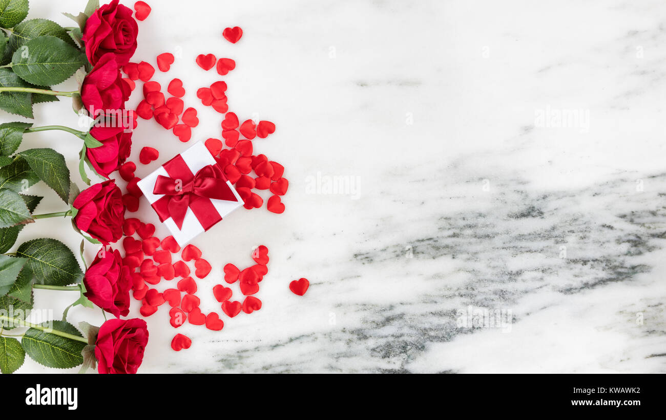 Roses rouges, cœur de formes et boîte-cadeau formant bordure gauche en arrière-plan en pierre Banque D'Images