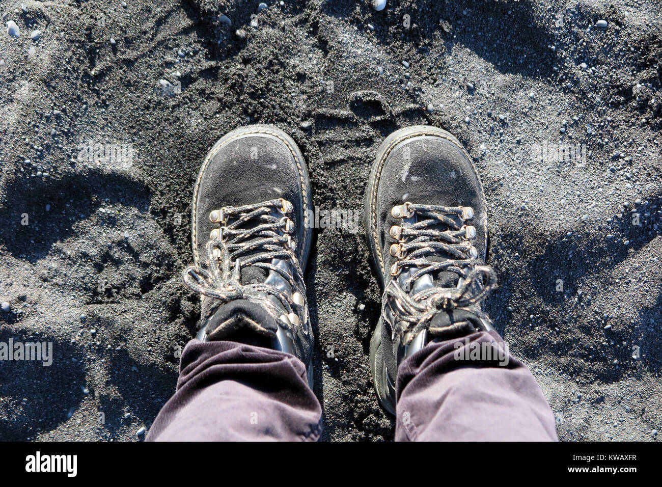 Des bottes noires sur la plage de sable noir, l'Islande Banque D'Images