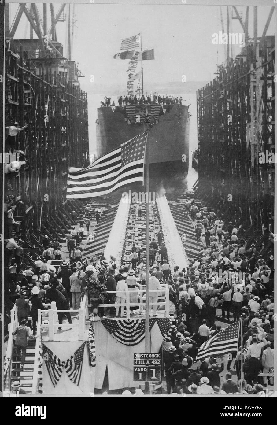 Élaborer le lancement du navire de guerre américain, Quistconck au Hog Island, chantiers navals, avec le président Woodrow Wilson et son épouse Mme Wilson debout à côté d'un grand mât-nous sur la plate-forme, avec la foule de personnes applaudissant et agitaient des drapeaux, et des hommes debout sur la poupe du bateau, Philadelphia, Pennsylvania, 1918. L'image de courtoisie des Archives nationales. Banque D'Images