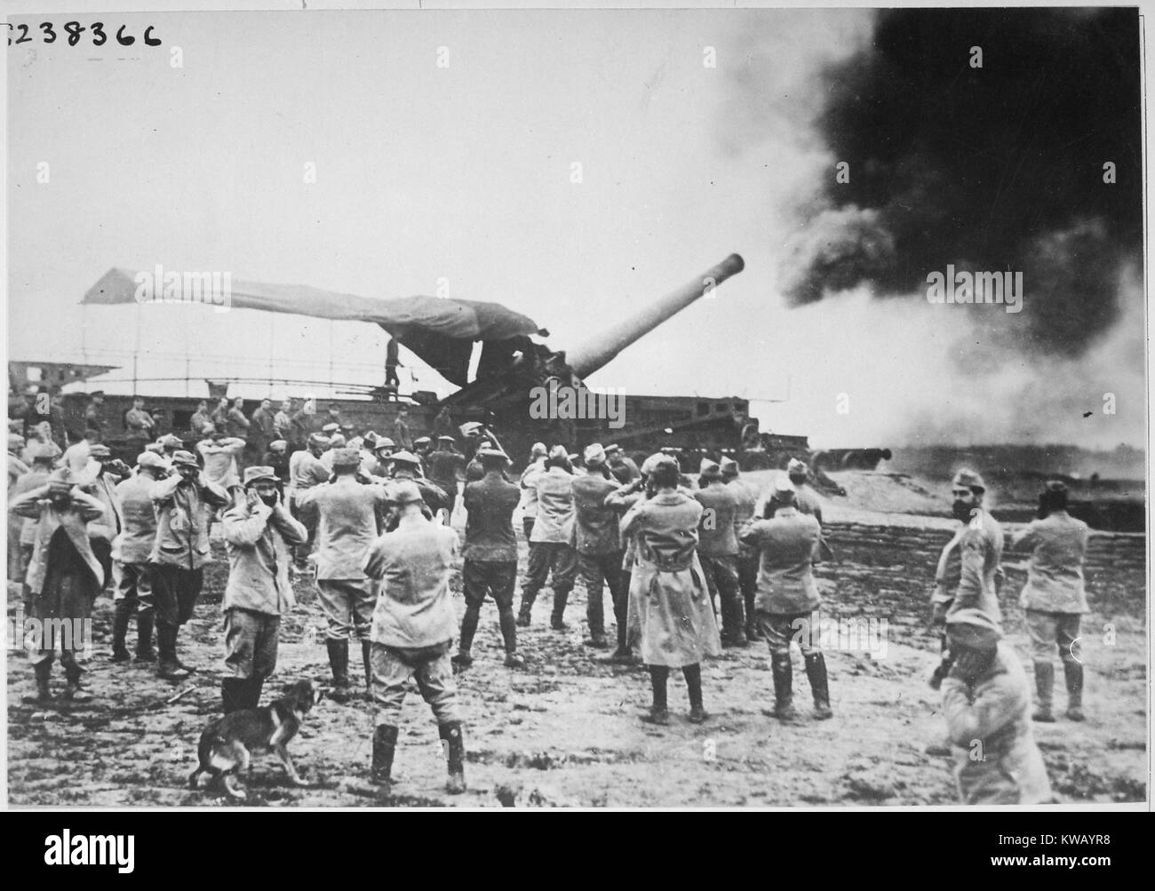 Sur les champs de bataille pendant la Première Guerre mondiale, un grand canon français se décharge et lance un shell à l'ennemi allemand, tandis que plusieurs des artilleurs se tenir autour d'essayer de protéger leurs oreilles, le son à partir de 1918. L'image de courtoisie des Archives nationales. Banque D'Images