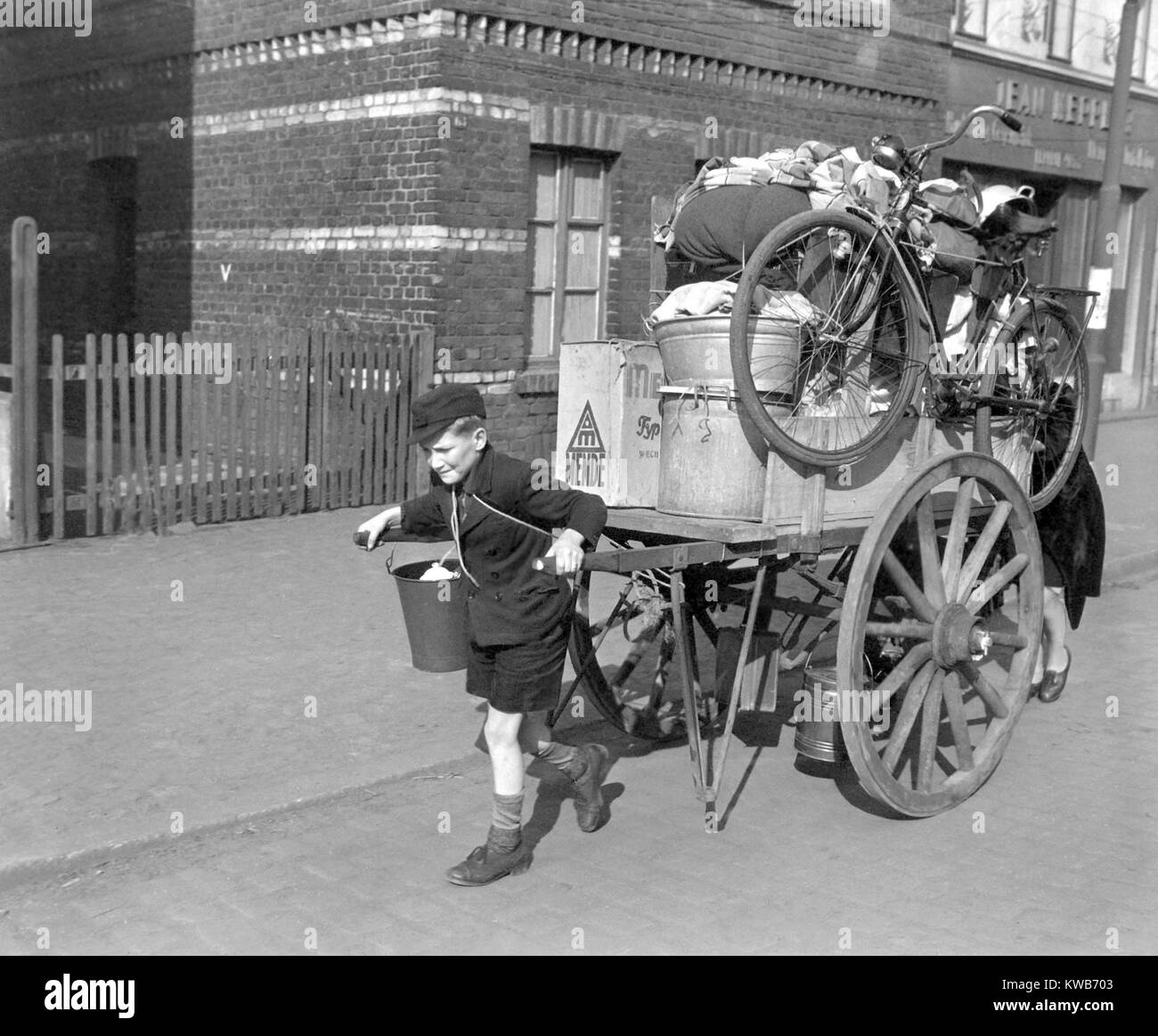 Un garçon tire, comme sa mère, pousse un chariot chargé avec leurs biens en Allemagne, Uerdingen. L'armée américaine a évacué les civils de la ville sur la rive ouest du Rhin le 19 mars 1945. La Seconde Guerre mondiale 2. (BSLOC 2014 8 85) Banque D'Images