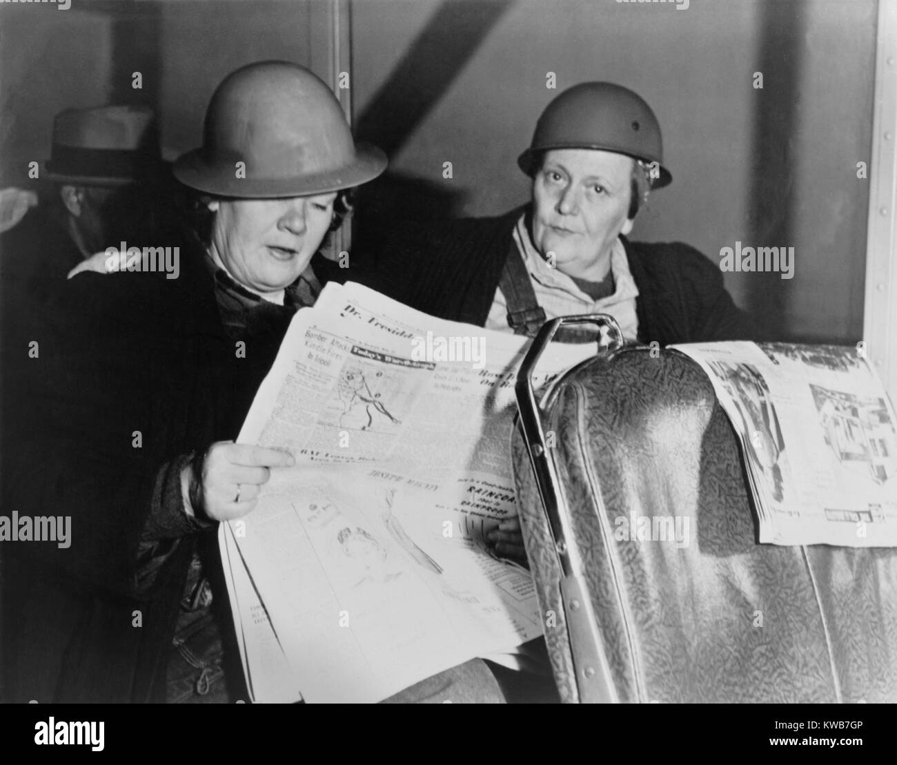 Après avoir travaillé toute la nuit, deux ouvriers de chantier naval femmes casqué lire le journal dans le bus à la maison. Ca. De 1940 à 1945. La Seconde Guerre mondiale 2. (BSLOC 2014 10 216) Banque D'Images