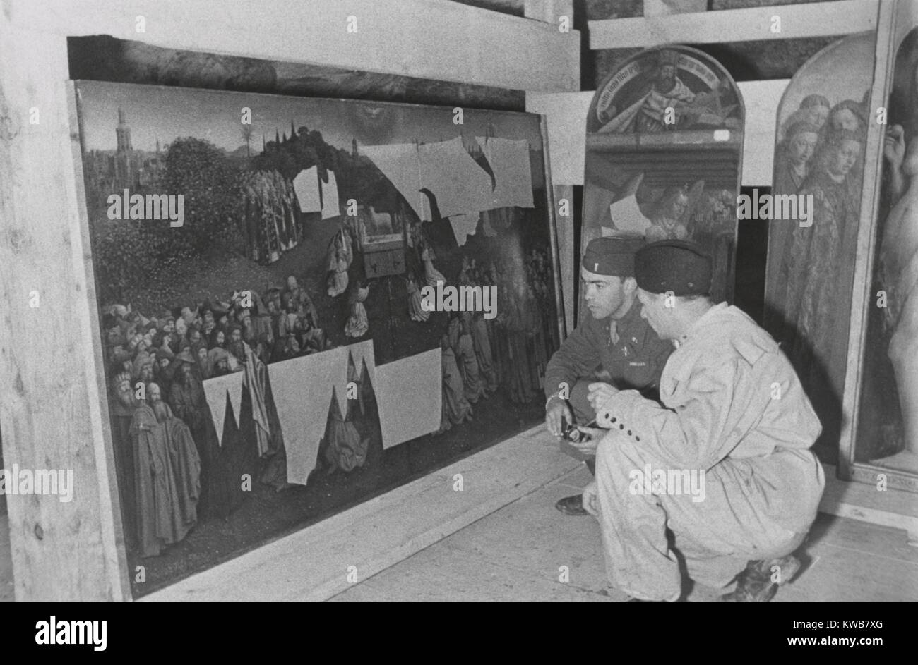 Des soldats de l'armée américaine examine l'ABAM Section Gand Retable de la mine, 1945 Altaussee. Le lieutenant Daniel J. Kern et restaurateur allemand Karl Sieber examiner Jan van Eyck "l'Adoration de l'Agneau Mystique", un panneau à partir de le retable pillés par les Allemands à partir de la Belgique en 1940. D'autres panneaux du retable sont démontés à la droite. Cette œuvre d'art était en vedette dans LES MONUMENTS MEN, un film de 2014 basé sur le livre de Robert M. Edsel. La Seconde Guerre mondiale 2. (BSLOC   2014 10 282) Banque D'Images