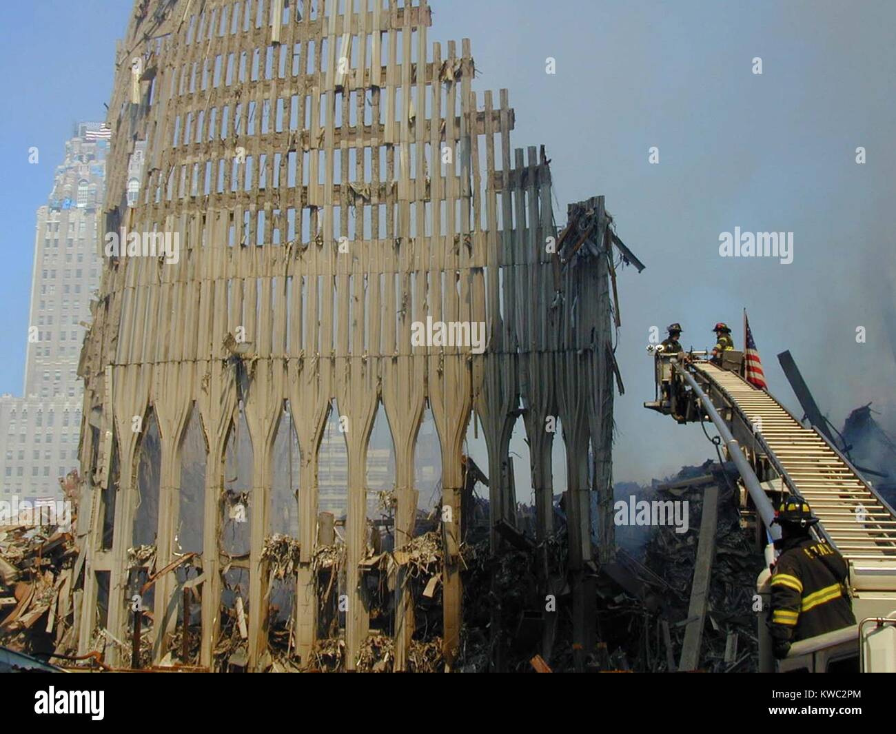 Les pompiers de New York dans un seau sur une échelle à coulisse sur les ruines du WTC 2, la tour sud. Le 16 septembre 2001. Il y a un drapeau sur le toit du New York Téléphone endommagé (Verizon) Bâtiment à gauche lointain. World Trade Center, New York City, après des attaques terroristes du 11 septembre 2001. (BSLOC 2015 2 87) Banque D'Images