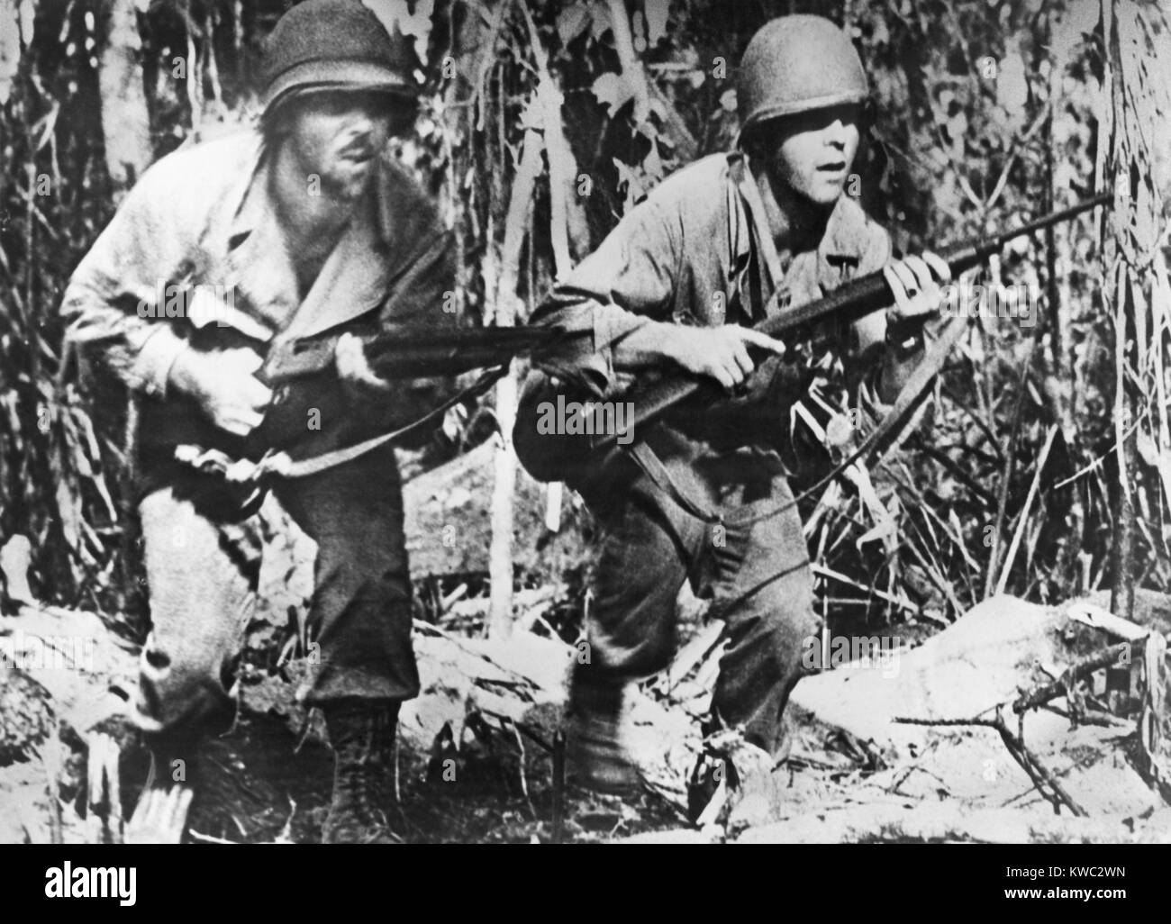 Deux soldats américains, à Bougainville, au cours d'attaque japonaise en mars 1944. La souche présente sur leurs visages comme ils l'avance dans les taillis où tireurs d'japonais sont actifs. World War 2 (BSLOC   2015 13 124) Banque D'Images