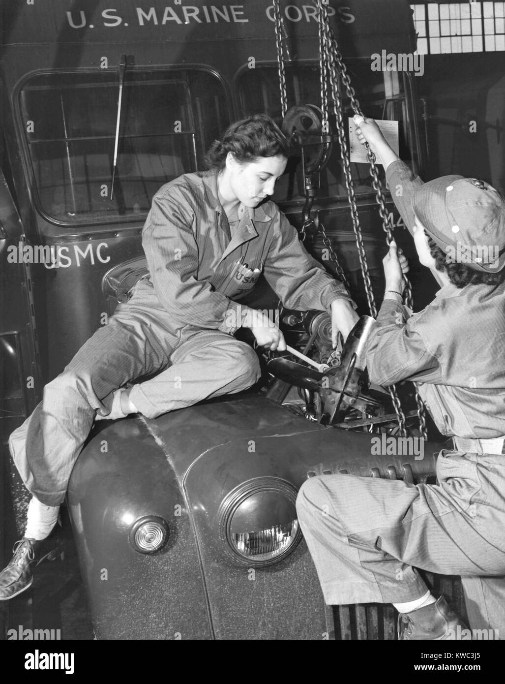 Les femmes Marines abaisser un moteur remis en place dans un bus du Corps des Marines en 1943. Ils sont diplômés de l'école en transport et sont attachés à la garage à Camp Lejeune, en Caroline du Nord, pendant la Seconde Guerre mondiale. (BSLOC   2015 14 118) Banque D'Images