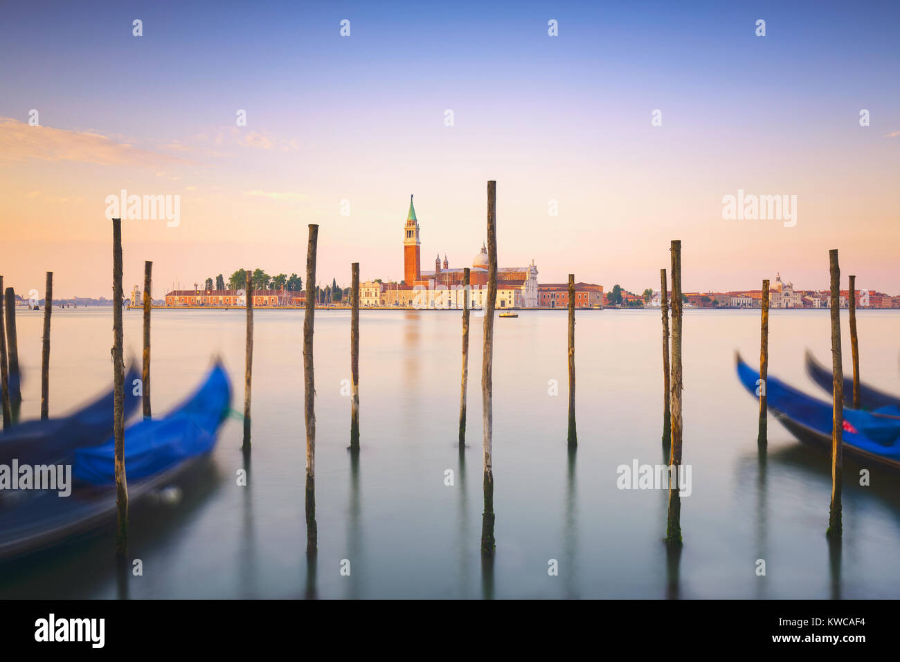 Lagune de Venise au lever du soleil, l'église San Giorgio Maggiore, gondoles et poteaux. L'Italie, l'Europe. Banque D'Images