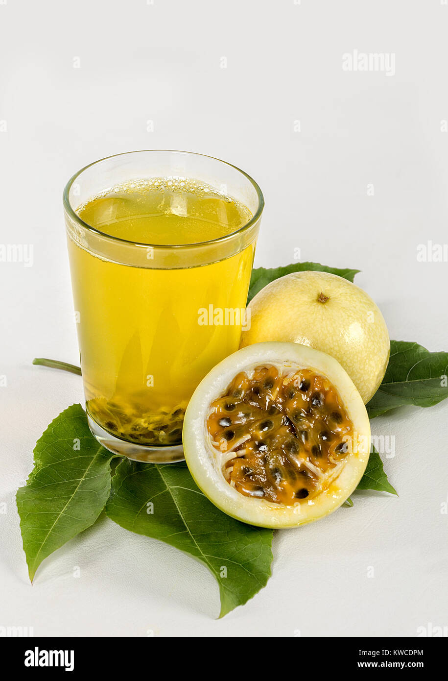 Un verre de jus de fruits de la passion et un fruit maracuya réduit de moitié sur une feuille maracuya Banque D'Images