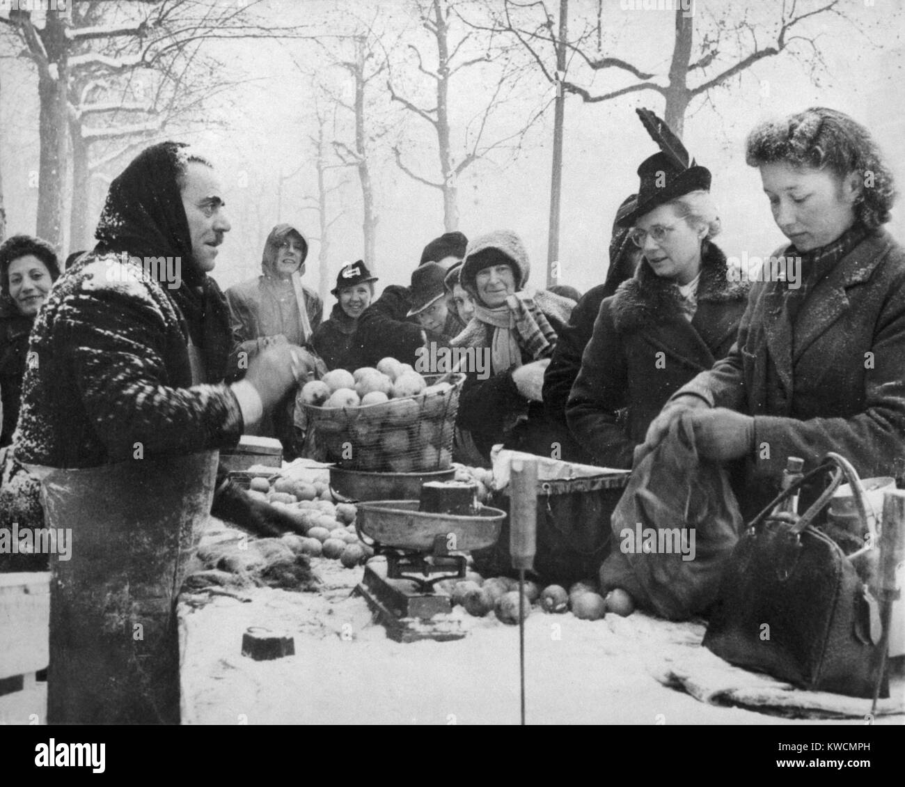 Les pommes d'achat des parisiens à un vendeur de rue dans la neige 1945. Le premier hiver après la libération était difficile pour les civils, en raison des pénuries de nourriture et de carburant. - BSLOC  2014 (15 240) Banque D'Images