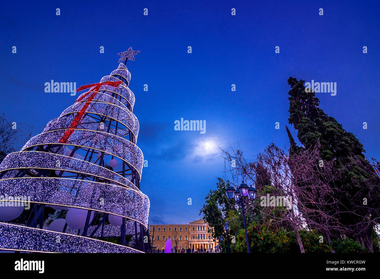 Allumé arbre de Noël dans la place Syntagma à Athènes, Grèce avec bâtiment du parlement européen à l'arrière-plan. Banque D'Images