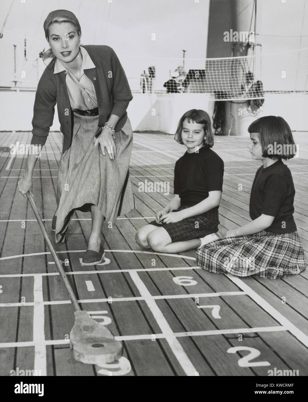 Grace Kelly en jouant le jeu de palets sur le pont de l'USS Constitution, le 10 avril 1956. Le navire a été arrêté à Algeciras, Espagne, sur ce chemin à Monaco où elle se maria au Prince Rainier III le 18 avril. Avec elle sont ses nièces, Margaret et Mary Lee Davis. - BSLOC  2015 (1 19) Banque D'Images