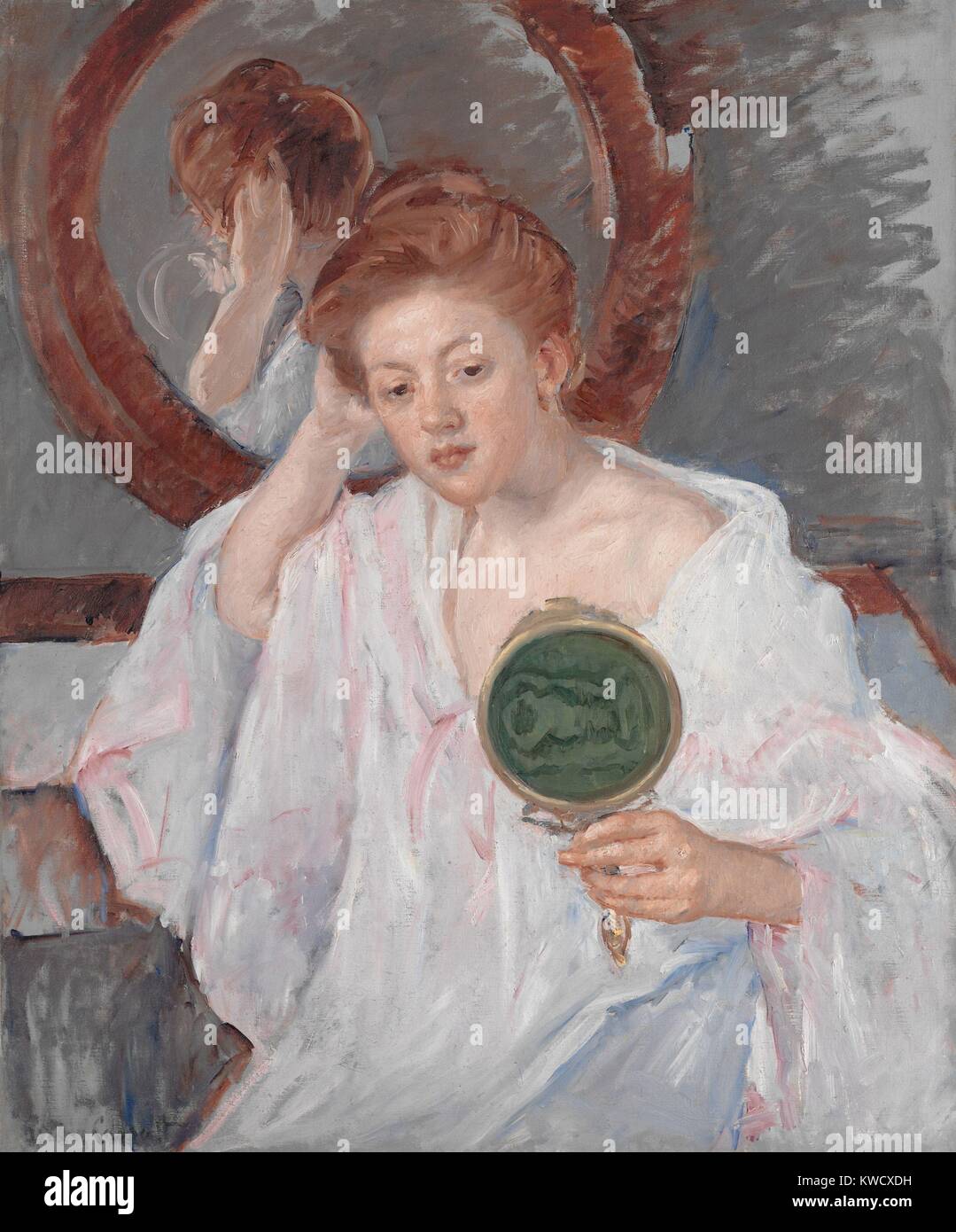 Denise à sa coiffeuse, par Mary Cassatt, 1908-9, la peinture impressionniste français, huile sur toile. Une jeune femme aux cheveux auburn étudie sa coiffure avec deux miroirs dans une composition picturale de brun chaud, roses et gris riche (BSLOC 2017 3 146) Banque D'Images