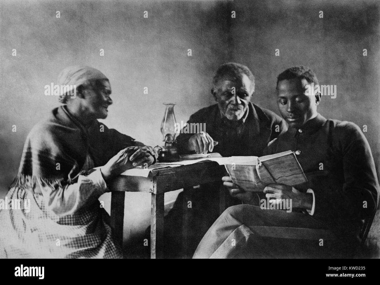 African American fils lire la Bible à ses parents, ch. 1890-1920. Cet écart entre les générations portrait de famille évoque l'espoir de progrès après l'esclavage. Le jeune homme porte un informer militaires semblables à ceux portés à Hampton et instituts de Tuskegee, African American Colleges de la période (BSLOC   2017 20 112) Banque D'Images