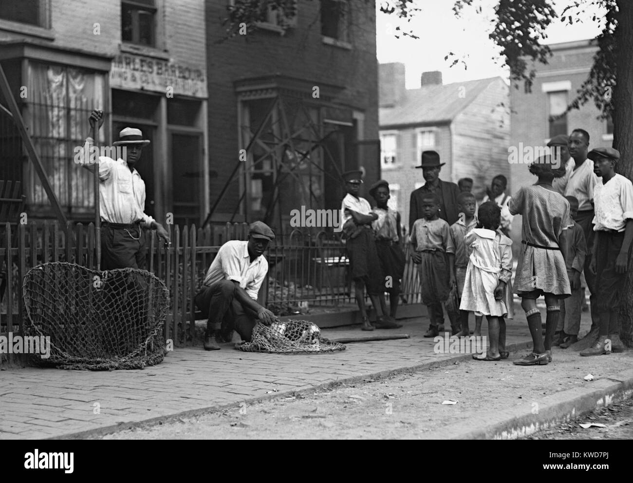 Les Africains américains travaillant comme sacs de chien à Washington, D.C. 1924. Un groupe de personnes se rassemblent autour d'eux sur le trottoir. (BSLOC   2015 16 125) Banque D'Images