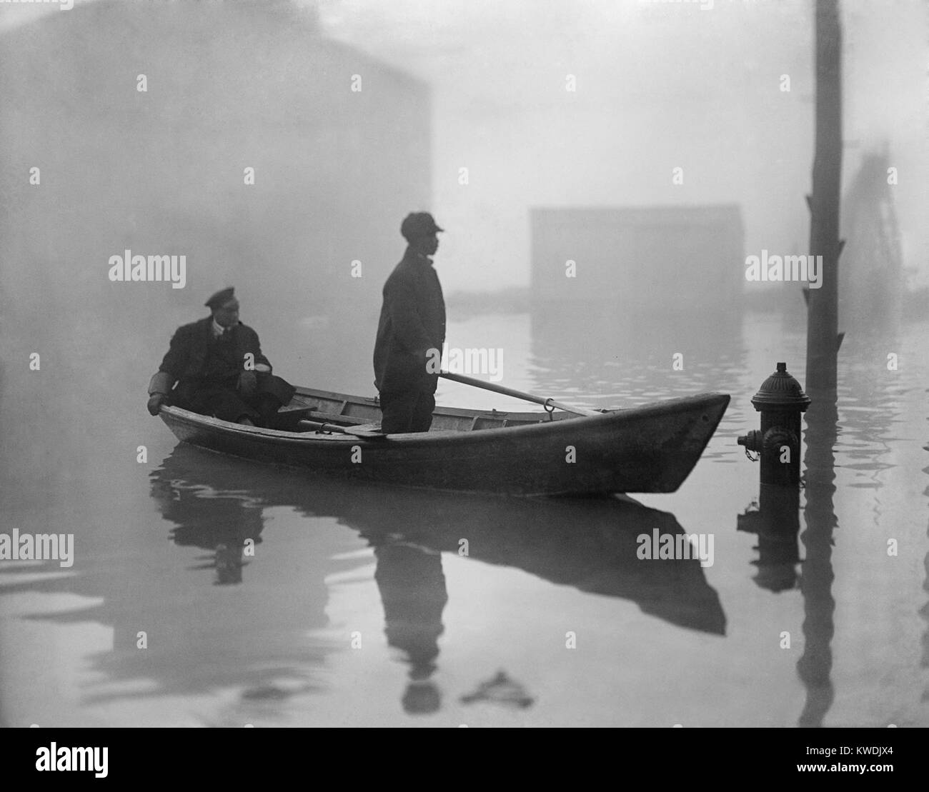 Un Afro-américain constitue un bateau dans Georgetown, au cours d'une inondation de la rivière Potomac 1910-09. Son passager assis porte un uniforme (BSLOC   2017 17 93) Banque D'Images