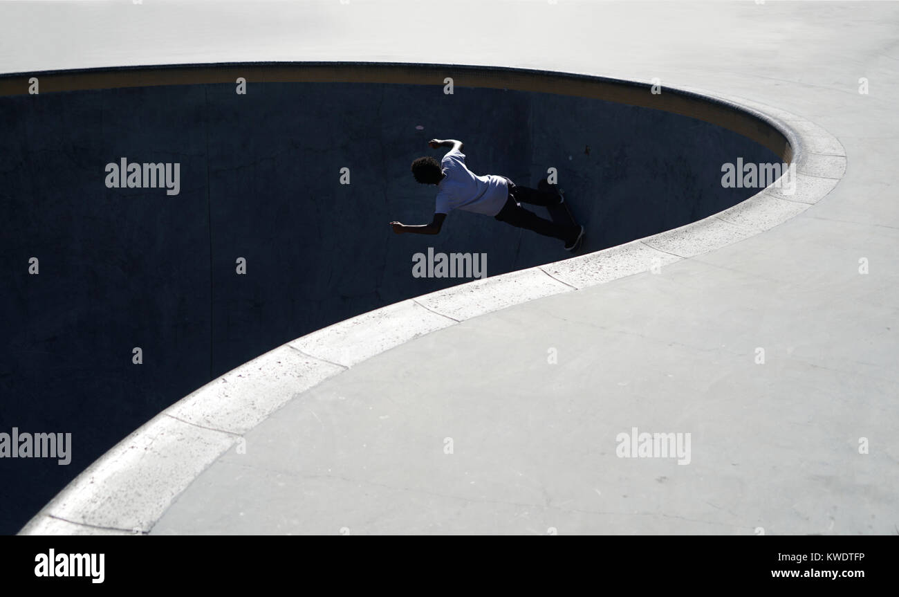 Un jeune skateur professionnel équitation dans la section de la piscine d'un skate parc au cours de l'été dans le Nord de la Floride. Banque D'Images