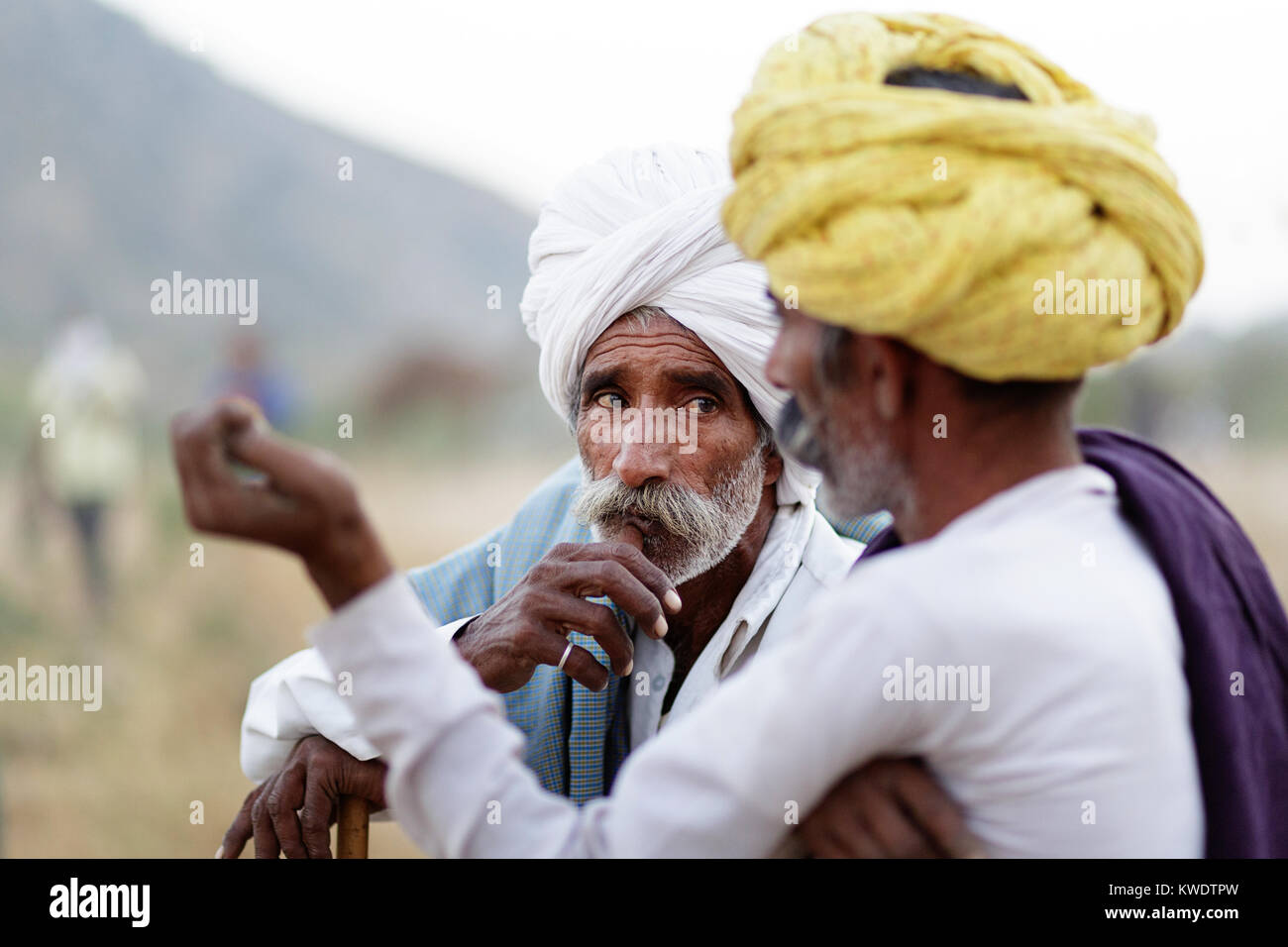 Scène à Pushkar Camel Fair, commerçants hommes fumer des cigares, parlant, la négociation pendant assis autour d'une cheminée à la fin de la journée de négociation, Rajasthan, Inde Banque D'Images