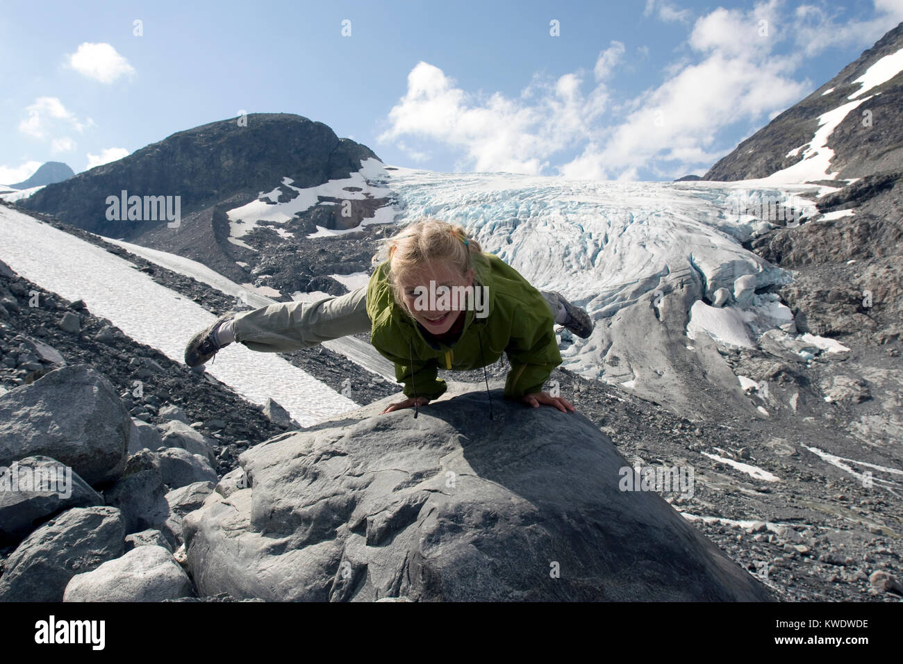 Huit ans fille blonde la gymnastique acrobatique de la scène en face de Storbreen au glacier de Norvège Jotunheimen Banque D'Images