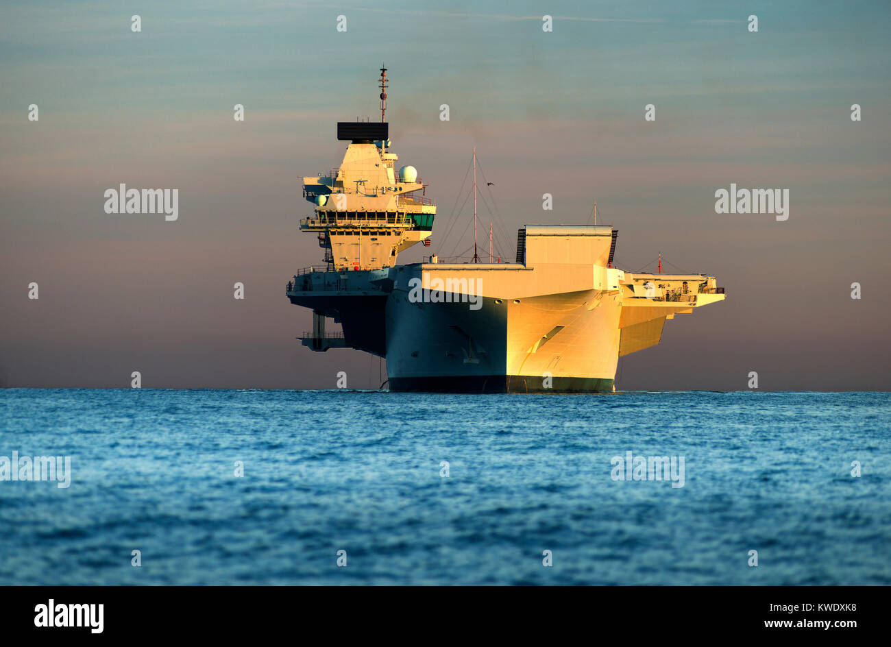 La Royal Navy porte-avions HMS Queen Elizabeth arrive au coucher du soleil à Portland, Dorset, sur la côte jurassique Banque D'Images