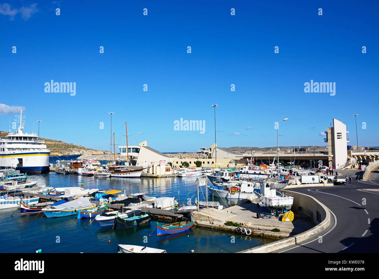 Bateau de pêche colorés amarrés dans le port avec le Gozo ferry amarré dans le port à l'arrière, Mgarr, Gozo, Malte, l'Europe. Banque D'Images