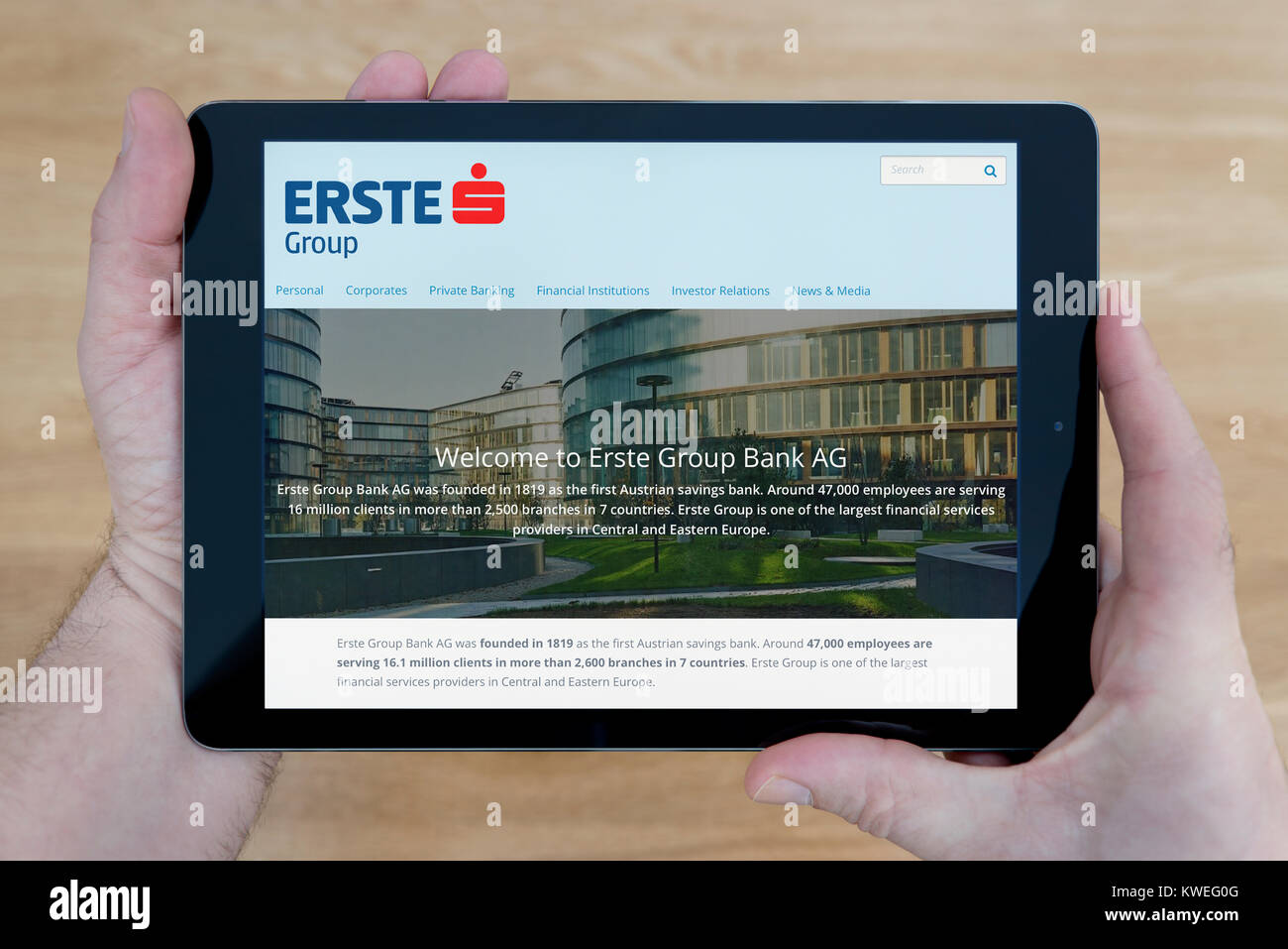 Un homme regarde la Erste Group Bank site sur son iPad tablet device, tourné contre une table en bois page contexte (usage éditorial uniquement) Banque D'Images