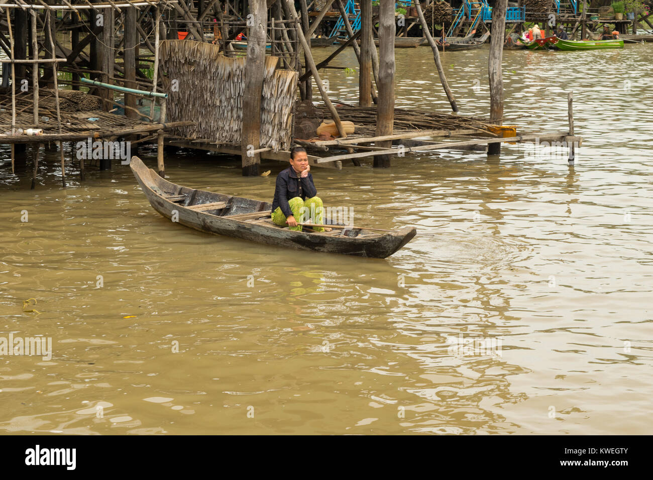 Une femme cambodgienne asiatique assis dans un canot en bois en attente sur l'eau du lac Tonlé Sap, de la plaine près de Kampong Phluk, le Cambodge, l'Asie du Sud Est. Banque D'Images