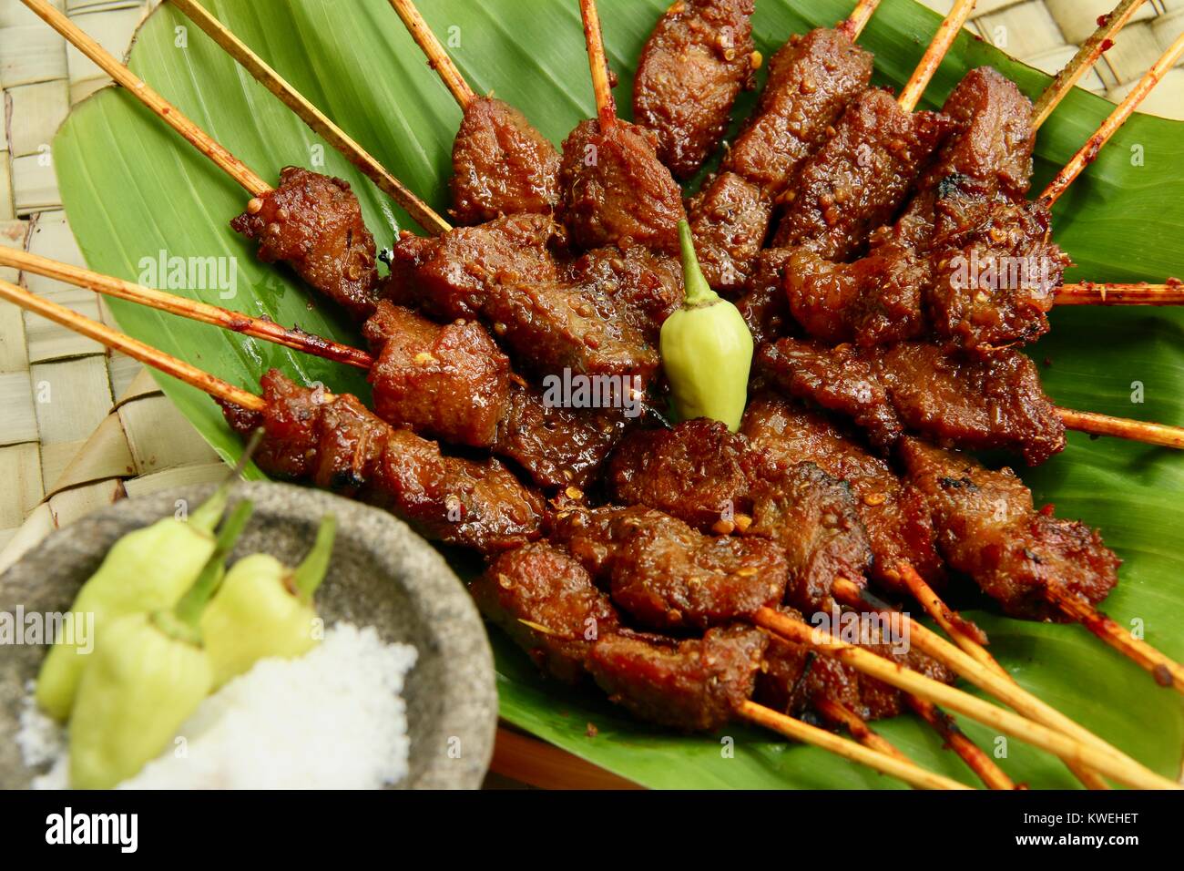 Sate Babi Bali. Satay de porc épicés balinais, servis avec des condiments sel de mer et de piments verts frais. Banque D'Images