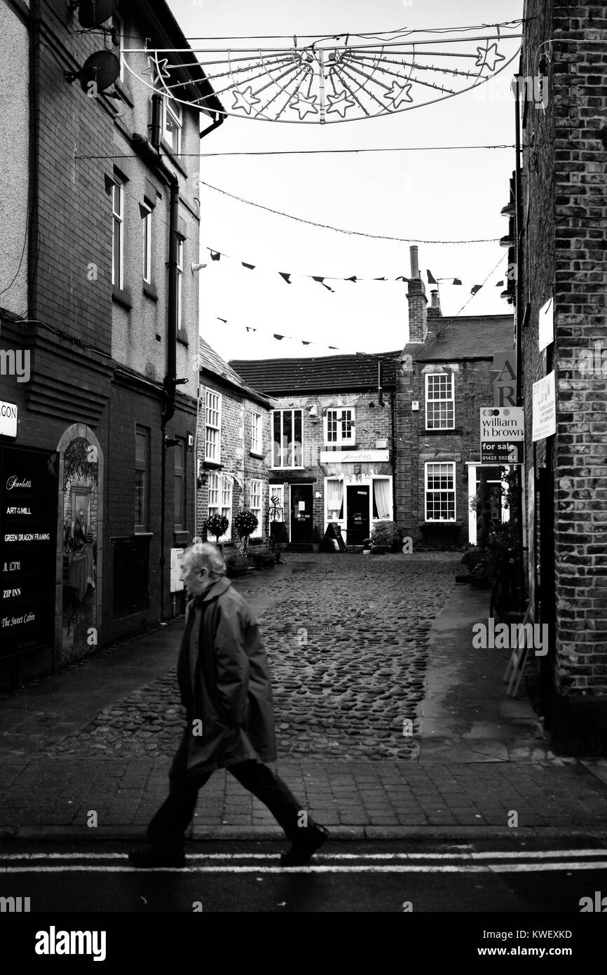 Homme marche devant l'entrée d'une route pavée à Knaresborough, Yorkshire du Nord. Banque D'Images
