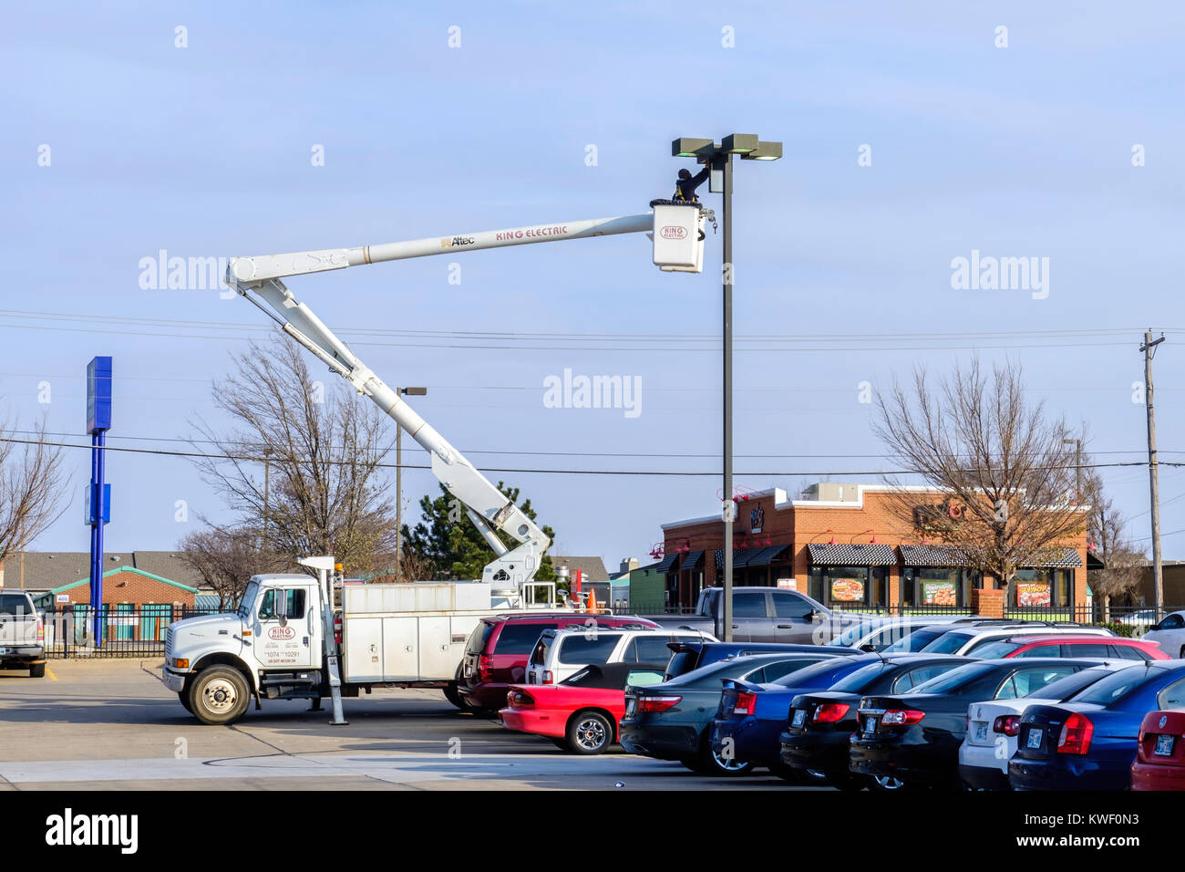 Un ouvrier dans un lever la benne fonctionne sur un centre commercial appareil d'éclairage. Oklahoma City, Oklahoma, USA. Banque D'Images