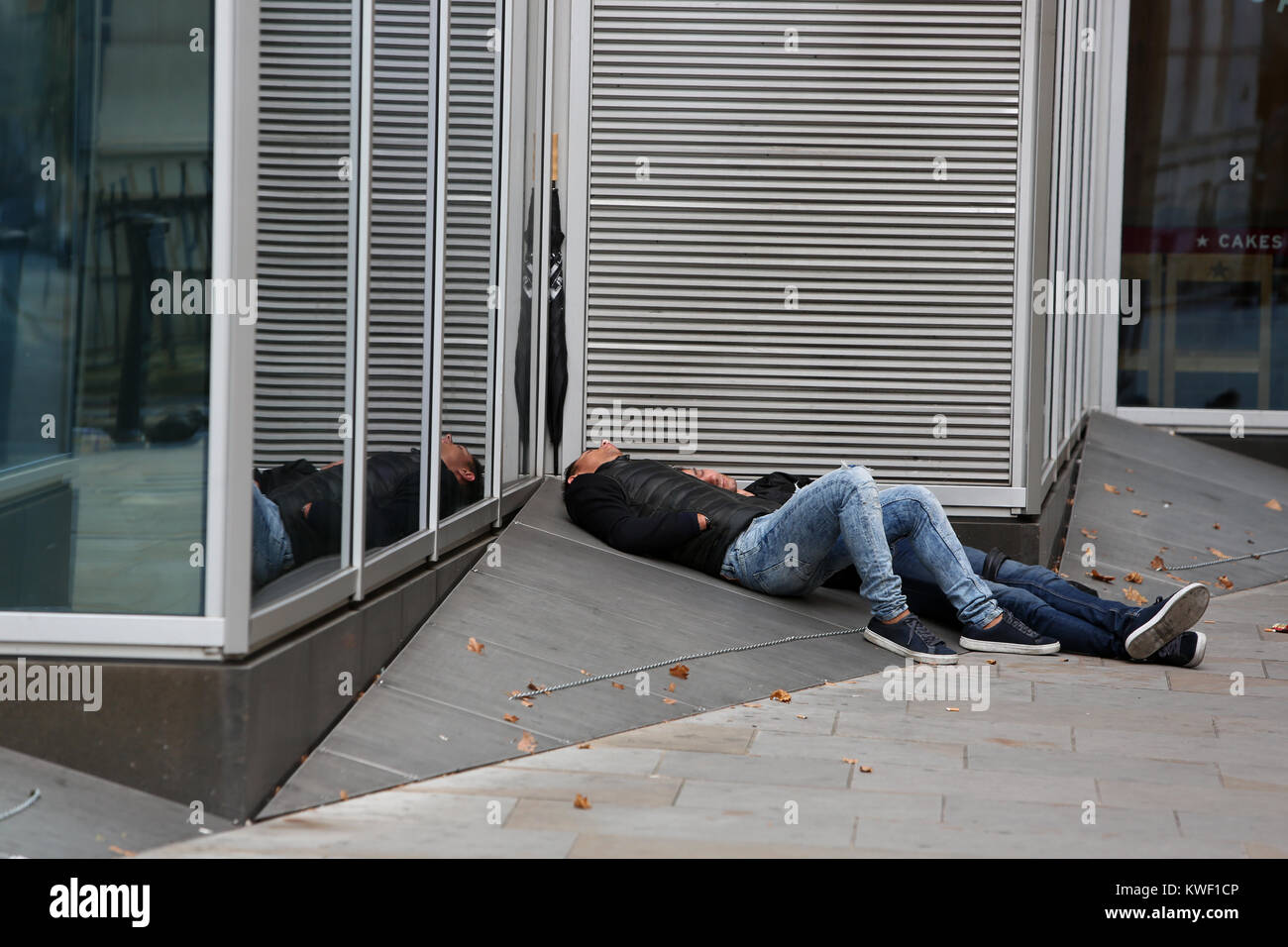 Deux hommes sans-abri dormant dehors sur un pret café à Londres, Royaume-Uni. Banque D'Images