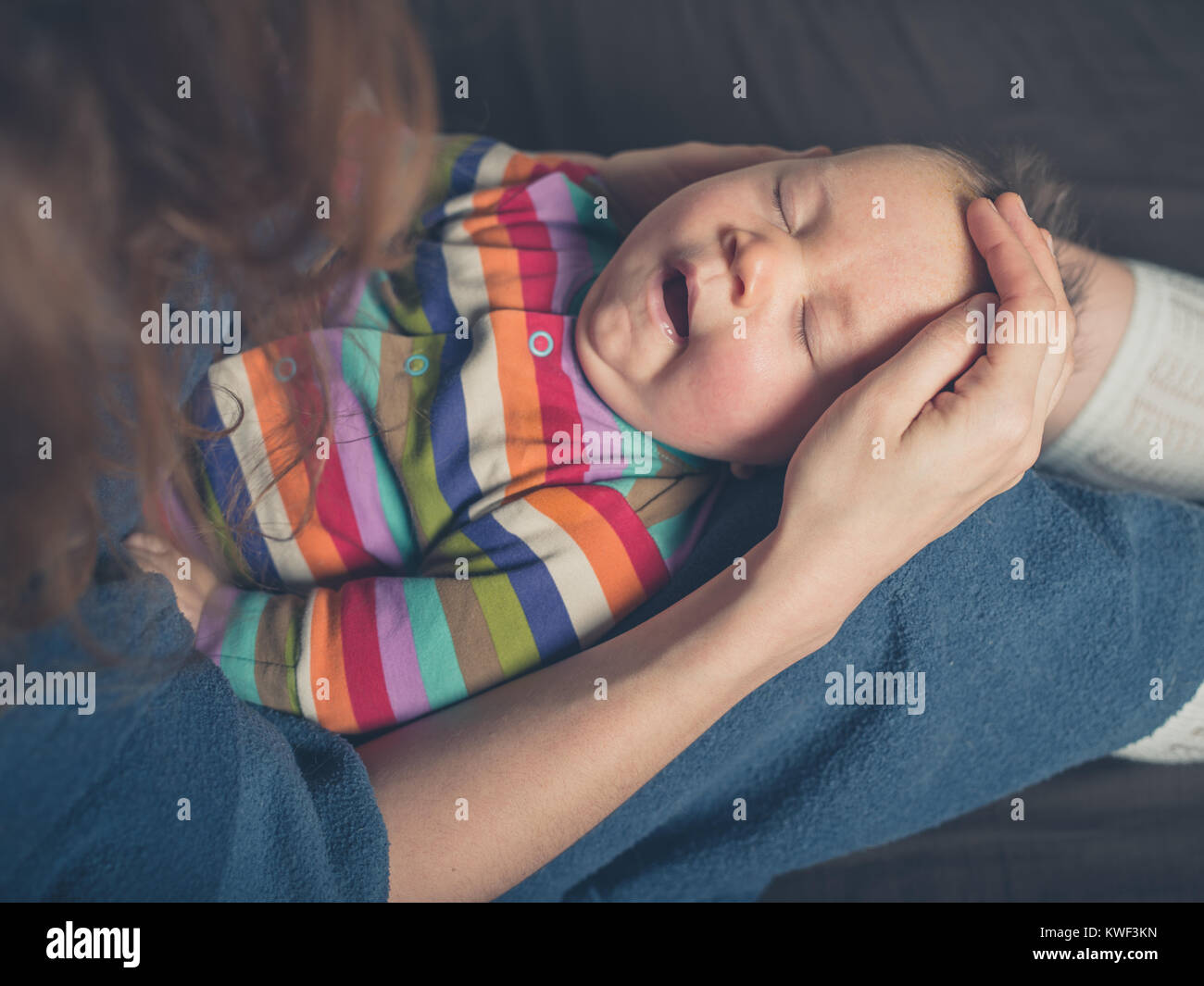 Une mère assis au lit est fatiguée holding yawning baby Banque D'Images