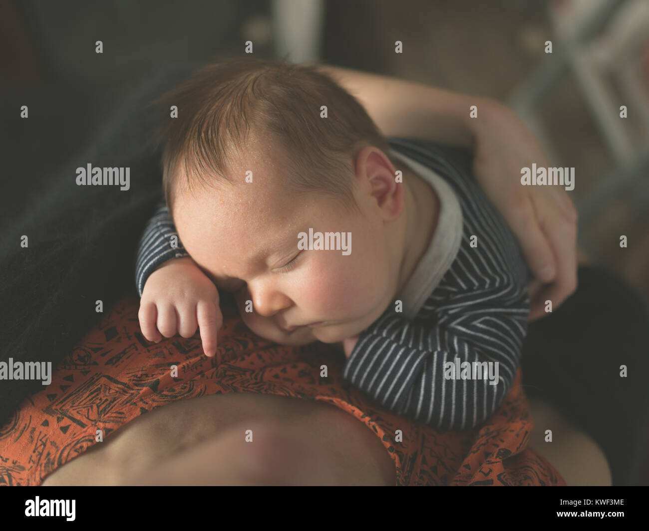Un jeune bébé dort comme sa mère le retient Banque D'Images